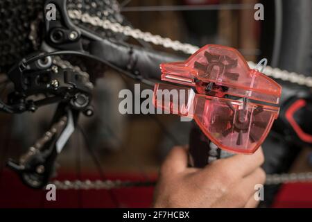 Nettoyage de la chaîne de bicyclette à l'aide d'un outil dédié au nettoyage. Conteneur en plastique avec brosses rotatives pour le nettoyage de la chaîne. Banque D'Images