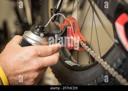 Nettoyage de la chaîne de bicyclette à l'aide d'un outil dédié au nettoyage. Conteneur en plastique avec brosses rotatives pour le nettoyage de la chaîne à l'état fermé. Banque D'Images