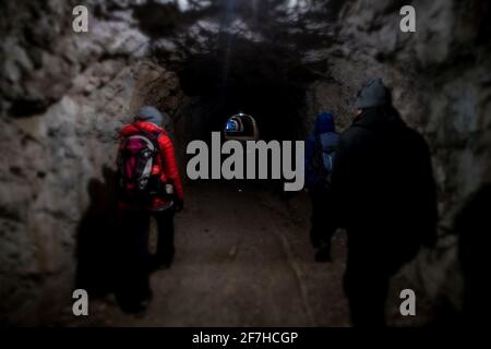 Un groupe de randonneurs marche dans un tunnel fait main sous la montagne. Des tunnels ont été faits dans la première guerre mondiale, dans les montagnes autour de Bovec, Slove Banque D'Images