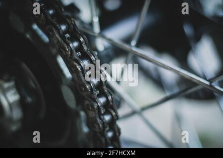 Détail d'une chaîne de moto montée sur un moyeu arrière. Photo grunge sombre d'une chaîne de vélo. Banque D'Images