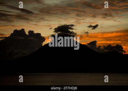 Vue en soirée sur la silhouette du volcan San Pedro, qui donne sur le lac Atitlan au Guatemala. Formations de nuages intéressantes sur le volcan. Banque D'Images