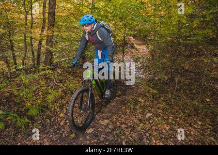 Vélo descendant avec vélo électrique moderne ou VTT en automne ou en hiver dans une forêt. E-cycliste moderne dans les bois. Banque D'Images