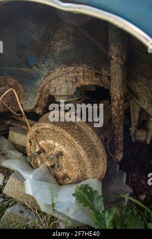 Freins à tambour fortement rouillés ou extérieur du tambour de frein avec ressort hélicoïdal et essieu arrière sur un véhicule d'époque abandonné. Il manque une roue sur un ancien bleu Banque D'Images