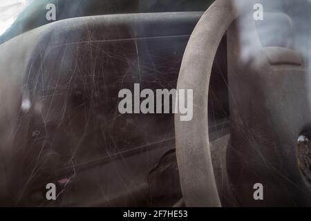 Tableau de bord recouvert de spiderwebs sur une voiture d'époque rouillé sur un terrain. Voiture abandonnée oldtimer, concept d'une voiture oubliée oldtimer. Banque D'Images