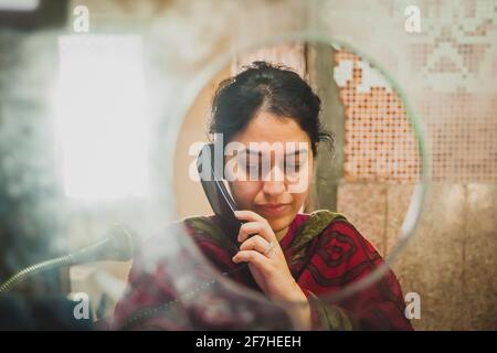 JAIPUR, INDE, 12 DÉCEMBRE 2016: Une femme indienne travaillant dans un bureau de billetterie sur une gare de Jaipur reçoit un appel téléphonique. Photo prise thr Banque D'Images