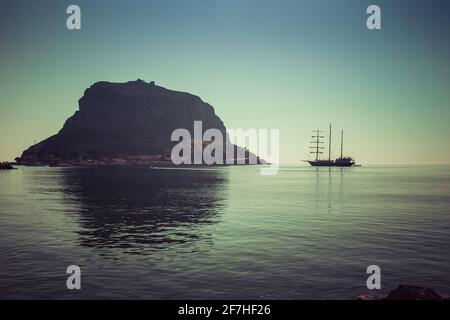 Vieille ville byzantine de roche de Monemvasia, un patrimoine de l'unesco sur Peleponese avec un vieux voilier naviguant à côté. Formation de roches sur la mer pendant la journée Banque D'Images