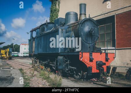 Une vieille locomotive à vapeur d'époque qui attend devant un hangar à Macomer, en Sardaigne, dans l'espoir de recevoir un nouvel avenir brillant en tant que locomotive de musée Banque D'Images