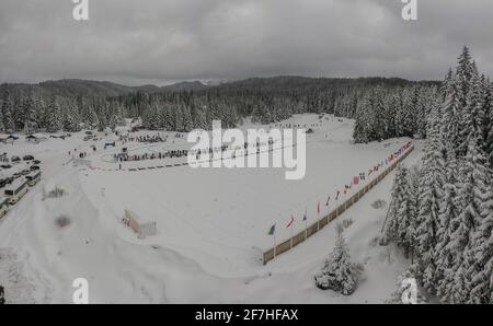 Vue aérienne par drone d'un stade de biathlon ou d'un lieu de tir, avec drapeaux nationaux visibles et forêts enneigées en arrière-plan près de Sarajevo sur le t Banque D'Images