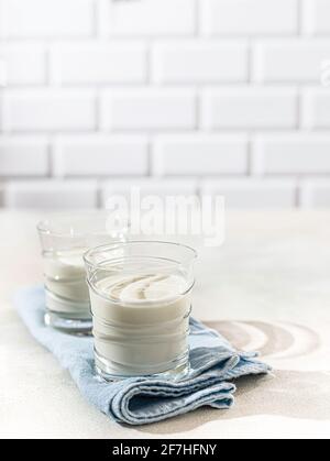 Boisson fermentée kéfir, yaourt dans un pot en verre sur fond clair. Boisson laitière fermentée froide probiotique. Concept de flore intestinale saine. Copier l'espace Banque D'Images