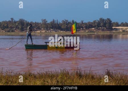 LAC ROSE, SÉNÉGAL, FÉVRIER 17 2017 : les touristes sur le lac Retba au Sénégal sont conduits dans un petit bateau avec un drapeau sénégalais. Banque D'Images