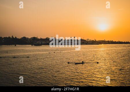 Coucher de soleil à Ziguinchor, Afrique, l'observant du pont sur la rivière casamance en direction du port de ferry. Un pêcheur avec bateau et filets sont voir Banque D'Images