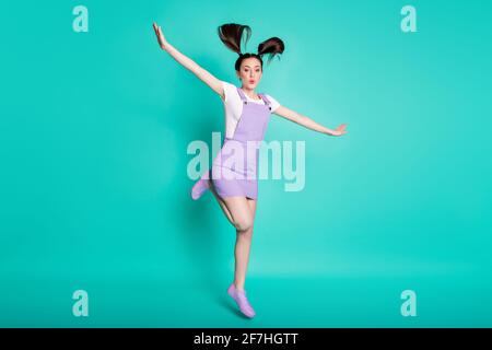 Photo de taille de corps pleine longueur de fille joueur puéril avec queues prétendant avion volant avec des ailes isolées sur sarcelle brillant couleur de fond Banque D'Images