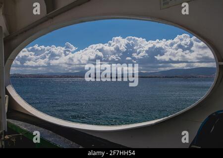 Un gros cargo ou transporteur traversant le détroit de Dardanele en Turquie par une journée nuageux, regardant à travers une fenêtre d'un ferry en direction de Canakk Banque D'Images