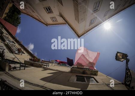 Chercher à voir les draps et les serviettes qui sèchent au soleil sur un balcon d'un bâtiment à Lisbonne, Portugal. Banque D'Images