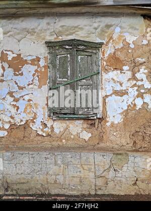 Mur et volet sur les fenêtres de la maison en argile en ruines abandonnée par ses propriétaires dans une région déprimée Banque D'Images
