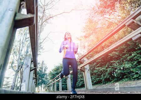 Jeune belle femme adulte courant sur un passage dans un concept d'auto-soin de sport de parc boisé au coucher du soleil Banque D'Images