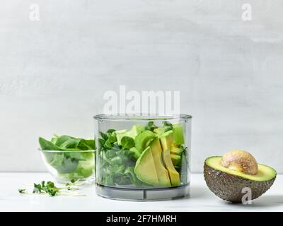 avocat, céleri et épinards dans un récipient en plastique transparent pour préparer un smoothie de petit déjeuner sain sur une table de cuisine Banque D'Images