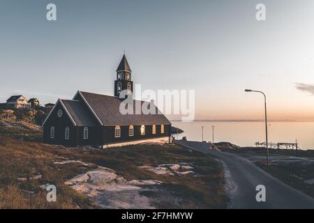 Ancienne église en bois de Zions dans la ville arctique d'Ilulissat, avec lumière du soleil de minuit et ciel bleu dans le nord du Groenland Banque D'Images