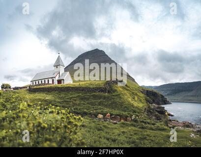 Vue sur l'église de Vidareidi également appelée Vidareidi Kirkja avec ciel nuageux, brouillard et montagnes. Îles Féroé, Danemark, Europe. Banque D'Images