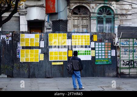 7 avril 2021, El Prado, la Paz, Bolivie. Un homme regarde des publicités pour des emplois disponibles sur un mur de fer ondulé temporaire autour d'un bâtiment historique abandonné dans le centre-ville. Banque D'Images