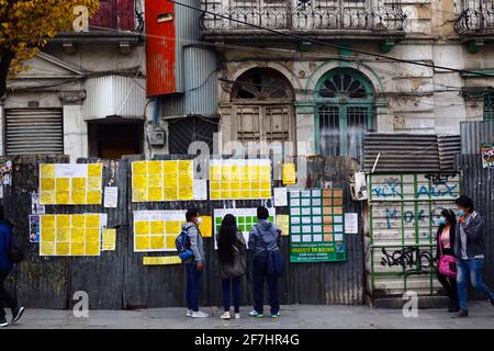 7 avril 2021, El Prado, la Paz, Bolivie. Les jeunes regardent les publicités pour trouver des emplois disponibles sur un mur de fer ondulé temporaire autour d'un bâtiment historique abandonné dans le centre-ville. Banque D'Images