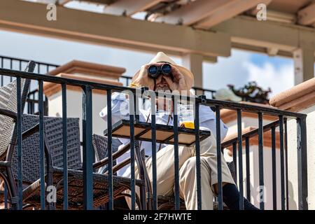 WEST PALM BEACH, FL - 14 MARS 2021 : homme avec chapeau de paille regardant un événement avec ses jumelles. Banque D'Images