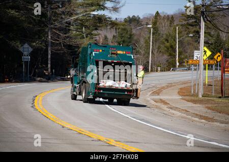 Un employé municipal de sexe masculin se trouvant à l'arrière d'un camion à ordures collectant des déchets dans le spéculateur, NY USA Banque D'Images