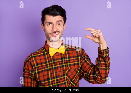 Photo de drôle douteux jeune gars porter chemise mesure petit espace vide isolé couleur violet arrière-plan Banque D'Images