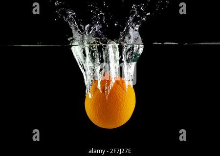 Le mandarin tombe dans l'eau sur un fond noir Banque D'Images
