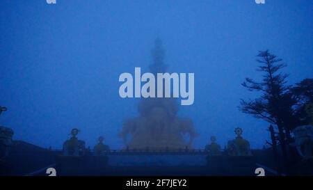Un Bouddha doré statues à peine visible dans le brouillard épais du matin sur le Mont Emei à Szechwan, en Chine. Banque D'Images