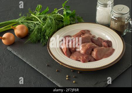 Foie de poulet cru dans un bol sur fond noir. Ingrédients pour la cuisson. Banque D'Images