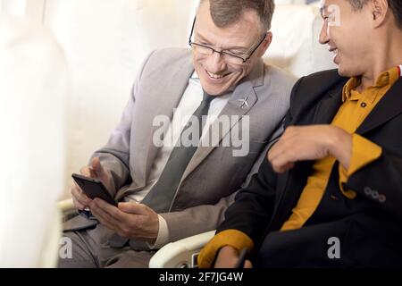 homme d'affaires avec costume assis à l'aide d'un smartphone dans le avion Banque D'Images