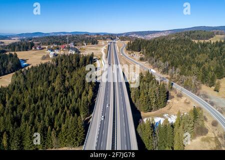 Ancienne route et nouvelle autoroute de Cracovie à Zakopane en Pologne, appelée Zakopianka avec viaducs, carrefour élevé et voitures. Vue aérienne en hiver. Banque D'Images