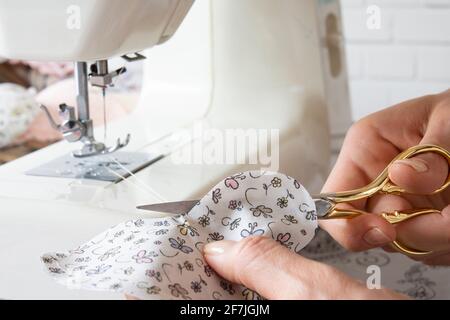 la femme de ménage coupe le tissu avec des ciseaux dorés Banque D'Images