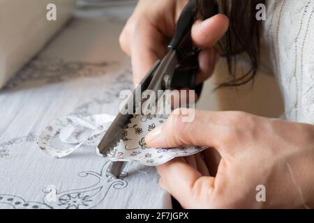 femme de ménage coupe le tissu avec des ciseaux dentelés Banque D'Images