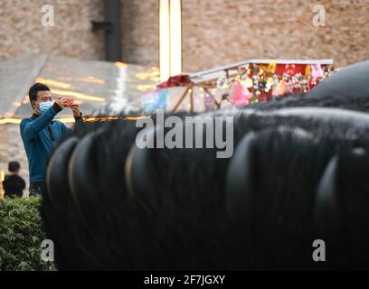 (210408) -- CHENGDU, le 8 avril 2021 (Xinhua) -- UN touriste prend des photos de la sculpture de 'Sefie Panda' sur la place Yangtianwo à Dujiangyan, dans le sud-ouest de la Chine, dans la province du Sichuan, le 7 avril 2021. Création de l'artiste néerlandais Florentijn Hofman, la sculpture a une dimension de 26,5 m sur 11 m sur 12 m, avec un panda géant à prise de selfie couché sur le dos. Pesant 130 tonnes, le travail prend forme à l'aide de trois millions de tiges en acier inoxydable peintes en laque. « Seelfie Panda » s'inspire d'un véritable panda géant qui s'est égaré dans le centre-ville de Dujiangyan en 2005. Il est rapidement devenu un spot photogénique populaire fol Banque D'Images