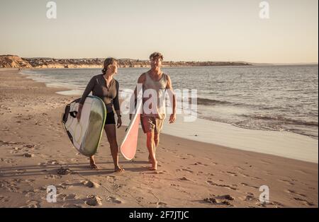 Couple d'âge mûr avec planches de surf sur la belle plage appréciant le paradis et le style de vie actif. Un homme et une femme séduisants surfent et s'amusent. Dans trave Banque D'Images
