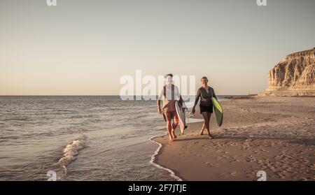 Couple d'âge mûr avec planches de surf sur la belle plage appréciant le paradis et le style de vie actif. Un homme et une femme séduisants surfent et s'amusent. Dans trave Banque D'Images