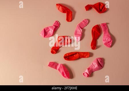 Composition minimaliste avec ballons dégonflés sur fond rose. Plusieurs nouveaux ballons rouges et roses. Vue de dessus, plan d'appartement. Banque D'Images