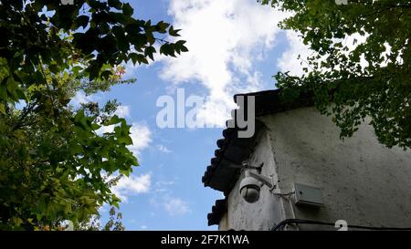 Une maison entourée d'arbres verts dans une journée ensoleillée avec un ciel bleu. Banque D'Images