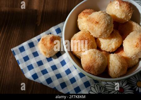 Petits gâteaux de noix de coco gros plan, dans un bol en céramique sur une table en bois avec une serviette bleue. Maison cuisine boulangerie. Banque D'Images