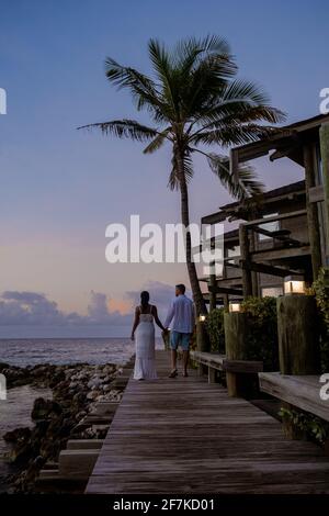 Resort de luxe tropical Curaçao avec plage privée et palmiers, vacances de luxe Curaçao Caraïbes, couple hommes et femme regardant le coucher du soleil à la plage avec piscine et palmiers, couple d'âge moyen plage Banque D'Images