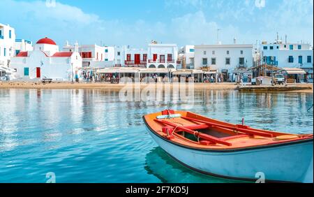 Belle journée d'été, île grecque en bord de mer. Bateaux de pêche, maisons blanchies à la chaux. Église dôme rouge. Petit bateau en premier plan. Mykonos, Cyclades, Grèce. Banque D'Images