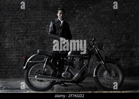 biker , coureur de café portant une veste en cuir noir debout derrière la moto britannique classique à Londres, Royaume-Uni Banque D'Images