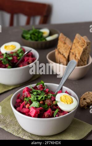 Vinaigrette russe à salade dans des assiettes avec œufs durs et pain noir, salade de légumes durs et marinés et pois verts en conserve Banque D'Images