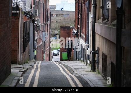 Homme marchant dans une petite rue étroite à Preston, Lancashire, Royaume-Uni. Banque D'Images