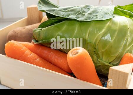 Carottes de chou et pommes de terre présentées dans un petit Crate en bois Banque D'Images