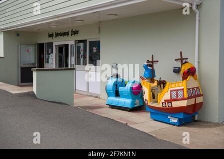 Manèges à pièces pour enfants (Teletubbies Noo Noo et Captain Pugwash) à l'extérieur d'un centre de divertissement familial dans le village côtier de Westward Ho!, North Devon, Angleterre. Banque D'Images