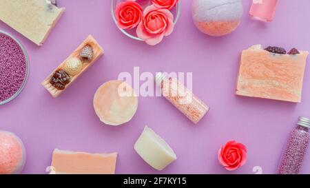 Produits de beauté Girly, produits spa pour l'hygiène du bain. Produits de beauté roses bombes de bain, perles de bain, huiles aromatiques et savon de fleur rose. Poser à plat sur le violet Banque D'Images