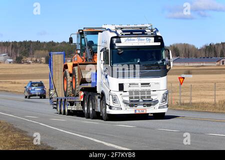 Le camion Volvo FH 540 de Lahma-Trans Oy transporte une chargeuse sur pneus Doosan sur une remorque surchargée le long de l'autoroute au printemps. Jokioinen, Finlande. 1er avril 2021. Banque D'Images